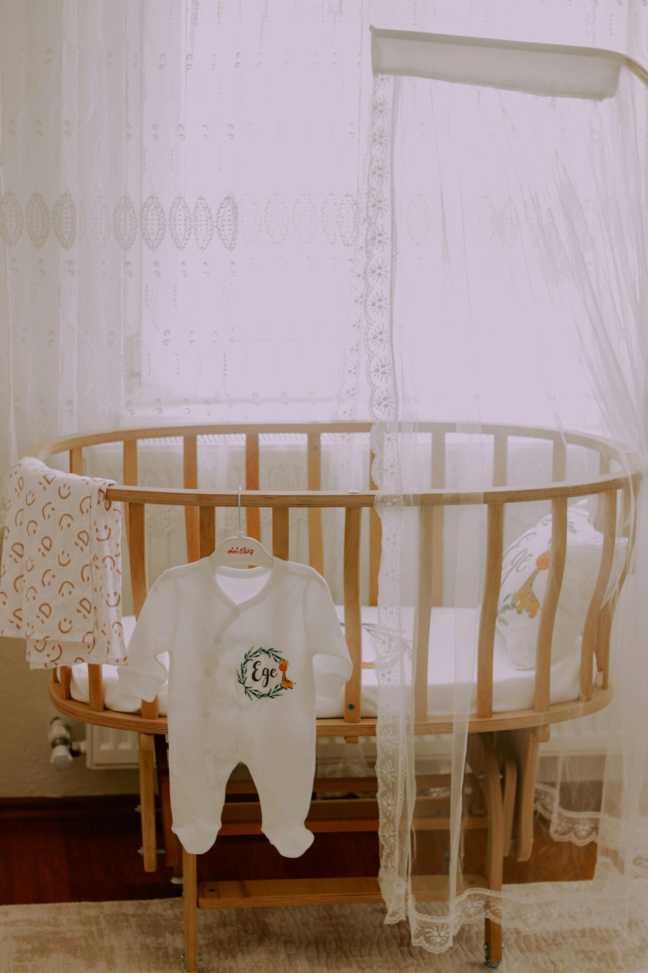 A serene baby room featuring a wooden crib and a cute baby outfit.