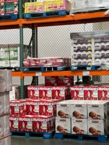 Stock photo of shelves filled with various baby diaper brands in a warehouse setting.