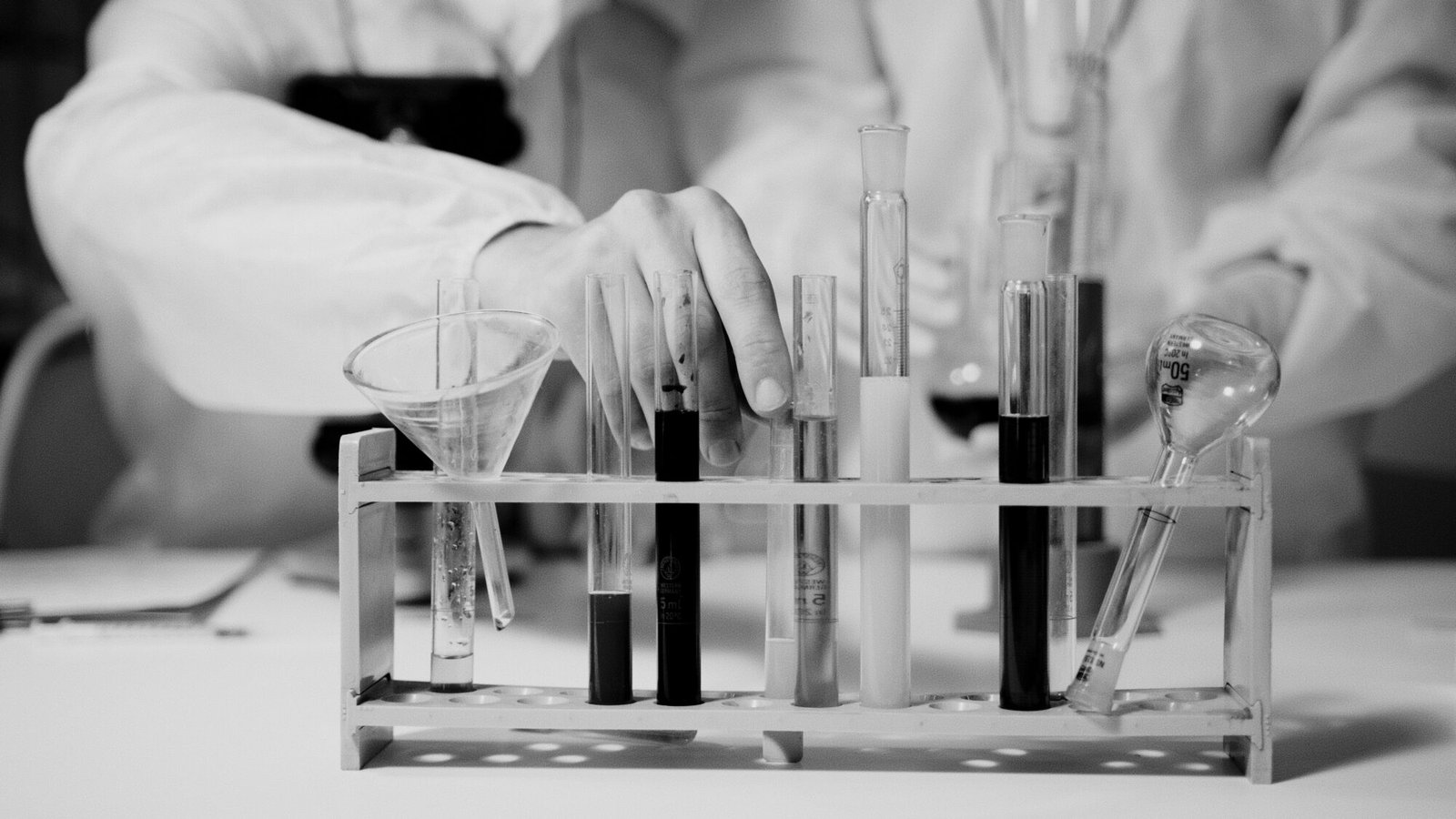 Scientist's hand handling test tubes in a laboratory experiment.
