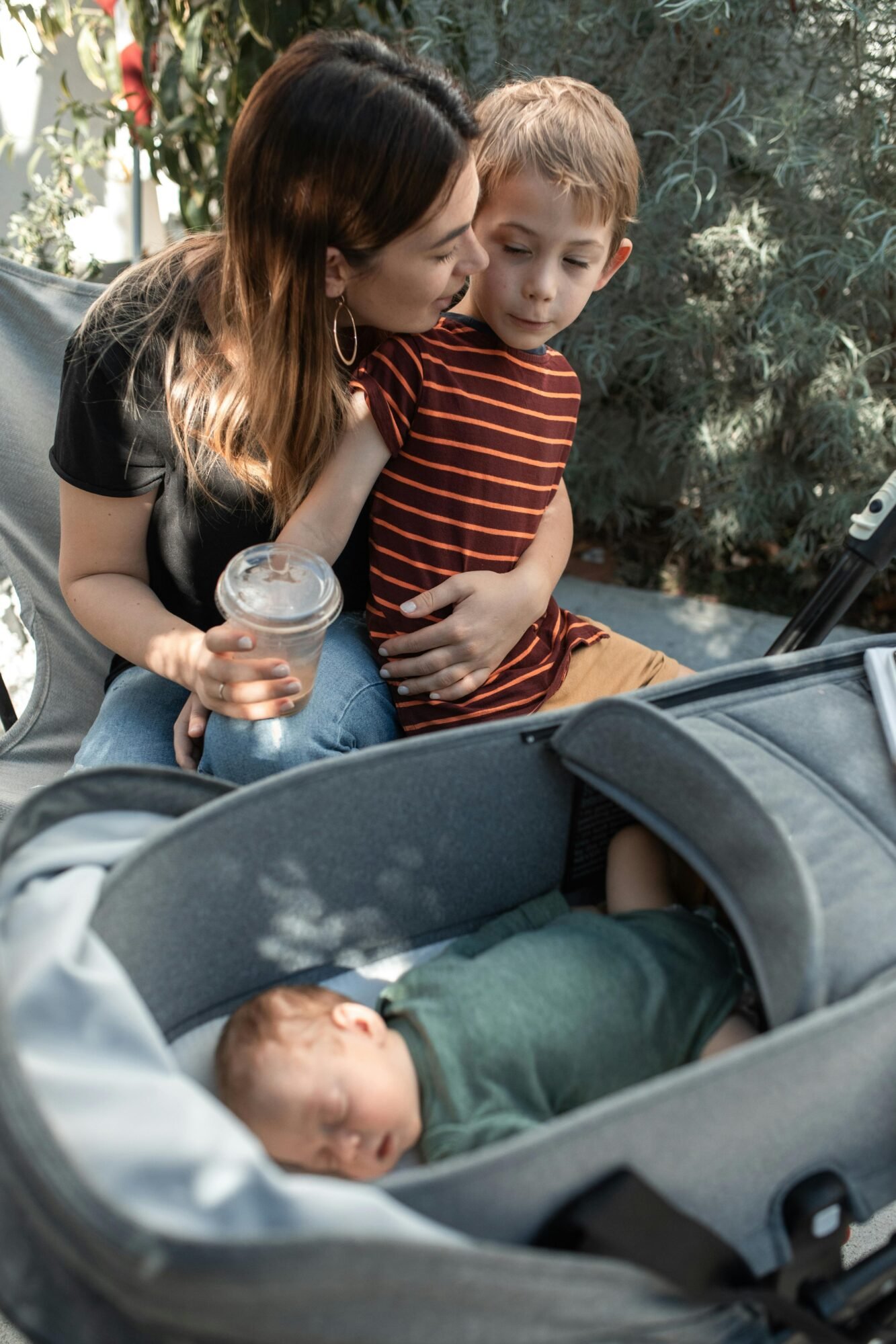 Family enjoying a sunny day; mother with her children, including a baby in a stroller.